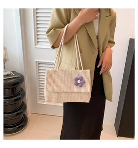 Modella indossa una borsa in paglia beige con trama a V e dettaglio floreale viola