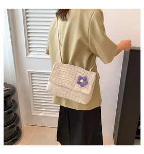 Dettaglio borsa a tracolla in paglia con fiore viola all'uncinetto su blazer oliva