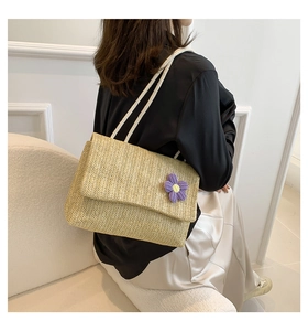 Dettaglio borsa in paglia intrecciata con fiore viola all'uncinetto e lacci
