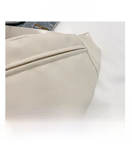 Close-up van de crème canvas borsttas met fijne stiksels en witte nylon schouderriem