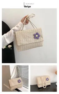 Detail of beige straw crossbody bag featuring a purple knit flower and dual rope straps