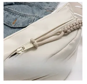 Detail van de soepele nylon rits met gevlochten trekker op een crèmekleurige tas
