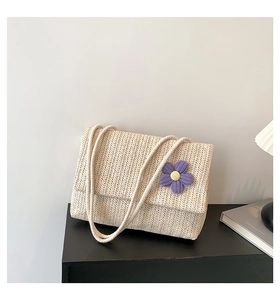 Dettaglio della borsa in paglia intrecciata con texture beige e fiore all'uncinetto