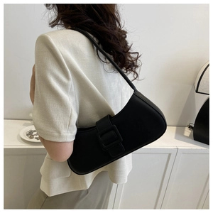Detail of a black leather baguette bag with a large square buckle for stylish women