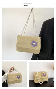 Detailed weave pattern on khaki straw tote bag featuring a purple crochet flower charm