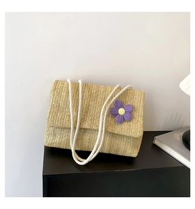 Dettaglio borsa a spalla in paglia intrecciata con fiore viola e manici in corda bianca