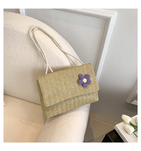 Dettaglio borsa in paglia intrecciata a mano con fiore viola in maglia e tracolla in corda
