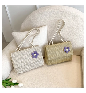 Dettaglio di borse in paglia intrecciata con fiori viola e tracolla in corda