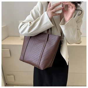 Grande borsa tote marrone con cuciture a V indossata da modella in abito formale
