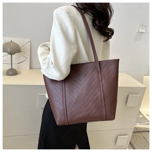 Dettaglio di borsa tote marrone scuro con cuciture a spina di pesce e finitura in ecopelle