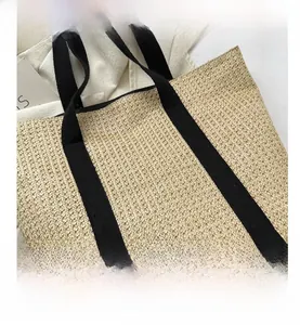 Close-up of the woven texture and black canvas strap stitching on a beige tote bag
