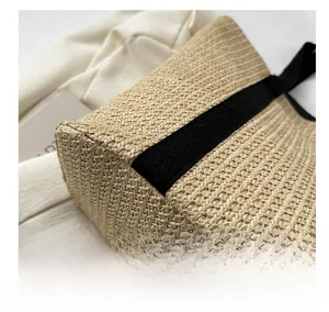 Detailed view of beige woven straw tote bag with premium fiber texture and black handles