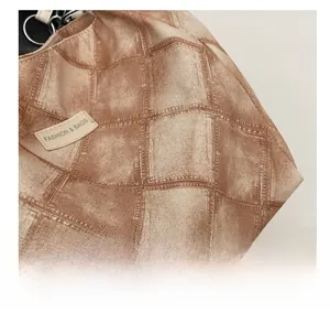 Detail of vintage checkered canvas texture and decorative brand tag on the shoulder bag