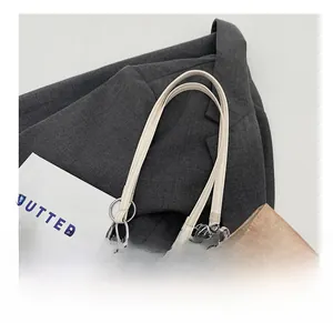 Detailed close-up of brown vintage leather bag with white strap and metal ring hardware