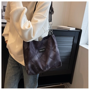 Detail of grey quilted tote bag with silver chain strap and fashion label on front