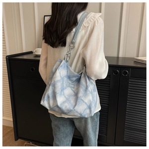 Close-up of blue and white tie-dye tote bag with silver chain strap and fashion label
