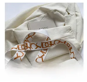Dettaglio borsa in pelle bianco crema con tracolla stampata e logo dorato