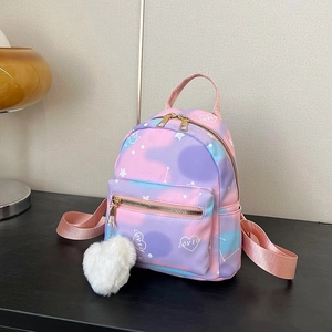 Mini gradient pink-purple backpack with heart print and plush heart charm on desk