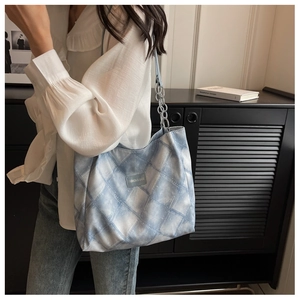 Close-up of light blue tie-dye tote bag with silver chain strap and leather logo patch