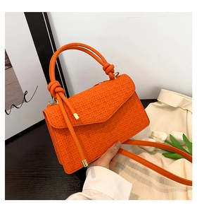 Détail du sac bandoulière orange tressé avec poignée à nœud et texture gaufrée