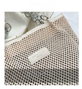 Detail of woven beige tote bag featuring silver chain rings and leather patch logo