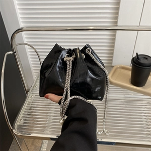 Mini black bucket bag with crocodile pattern, silver chain, and large pearl pendant charm
