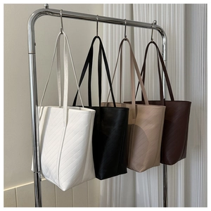 Borse tote trapuntate nei colori bianco, nero, beige e marrone appese a ganci in metallo