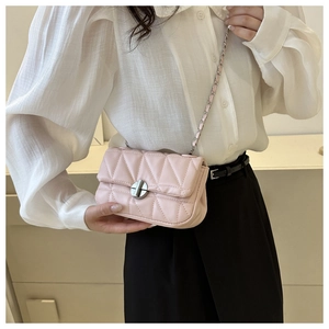 Détail d'un sac bandoulière rose clair matelassé avec fermoir rotatif argenté et chaîne
