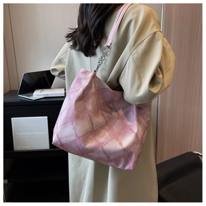 Detailed view of pink quilted canvas tote bag with chain strap and leather logo patch