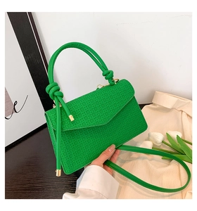 Détail du sac à main vert vif à texture tissée avec poignée nouée et rabat enveloppe chic