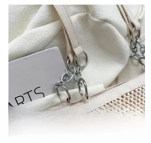 Detail of woven mesh texture and silver chain strap on beige tote bag with premium hardware