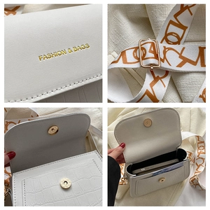 Dettaglio mini borsa bianca a coccodrillo con scritta moda e tracolla in tessuto