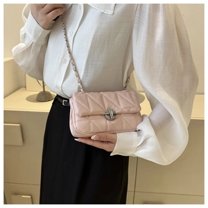 Detail of pink quilted crossbody bag with silver chain strap and metal swivel lock