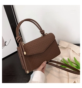 Détail du sac bandoulière marron vintage avec poignée nouée et garniture en métal doré