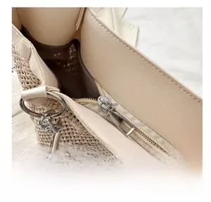 Close-up of woven tote bag showing silver zipper closure and beige leather trim details