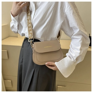Dettaglio borsa a sella beige con trama a coccodrillo e ampia tracolla con fantasia