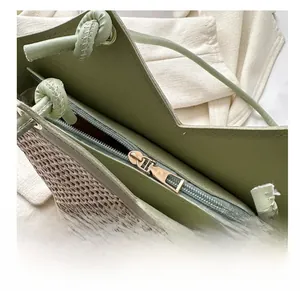 Détail de la fermeture éclair et des finitions en cuir vert du sac cabas en paille