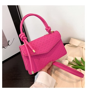 Détail du sac carré rose fuchsia avec texture tressée et poignée à nœuds dorés