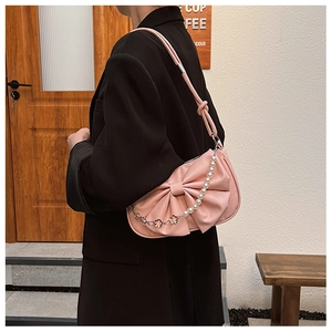 Détail du sac à bandoulière rose avec nœud et chaîne décorative en perles et métal