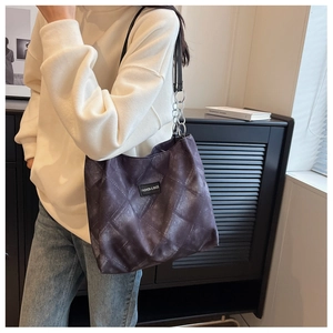 Close-up of diamond-quilted tote bag with chain strap and fashion logo patch