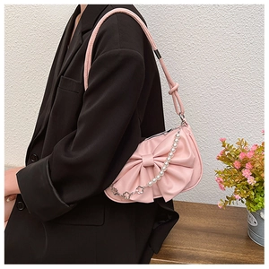 Détail du sac à bandoulière rose avec un grand nœud et une chaîne de perles décorative