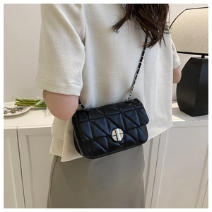 Detail of black quilted chain bag featuring silver rotary lock and faux leather texture