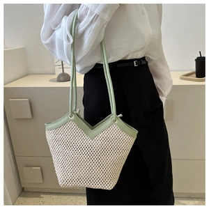 Détail du sac cabas en paille tissé avec lanières en cuir vert clair et maille