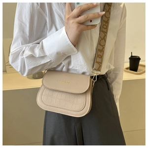 Dettaglio borsa a tracolla beige con trama a coccodrillo e ampia tracolla jacquard
