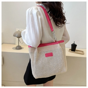 Detail of a woven tote bag featuring rose red leather trim and metal chain strap