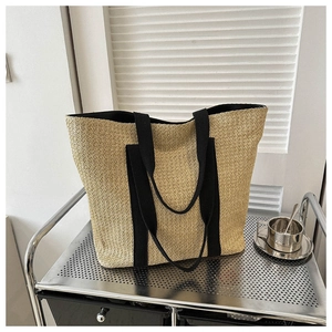 Detailed close-up of woven tote bag with black canvas straps on a minimalist metal shelf