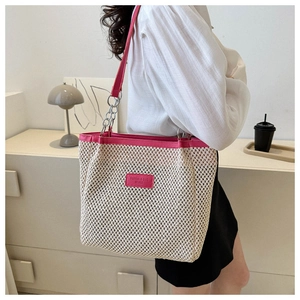 Detail of woven mesh tote with pink leather handle and silver chain on female shoulder