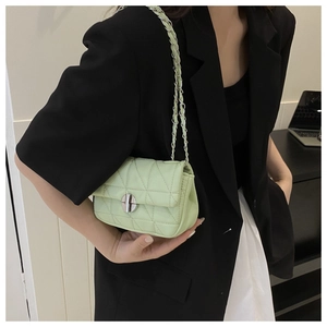 Close-up of mint green quilted crossbody bag with metal lock and chain strap detail