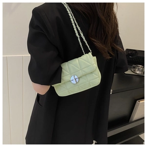 Detail of light green quilted crossbody bag featuring metal chain strap and twist lock closure