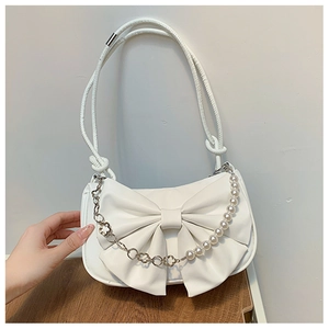 Détail du sac à bandoulière blanc avec grand nœud et chaîne en perles élégante